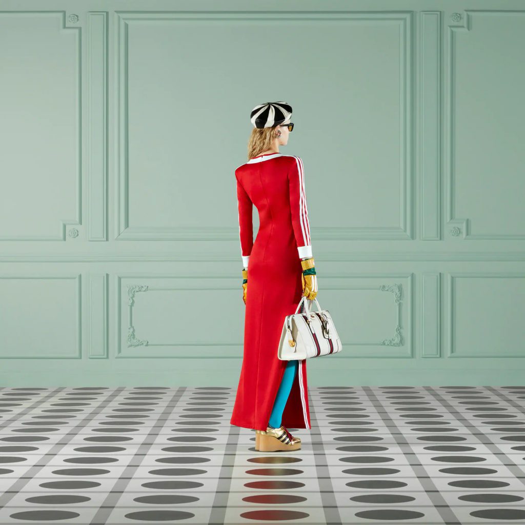 Người mẫu mặc váy đỏ và kính râm đi trên sàn nhà hoa văn