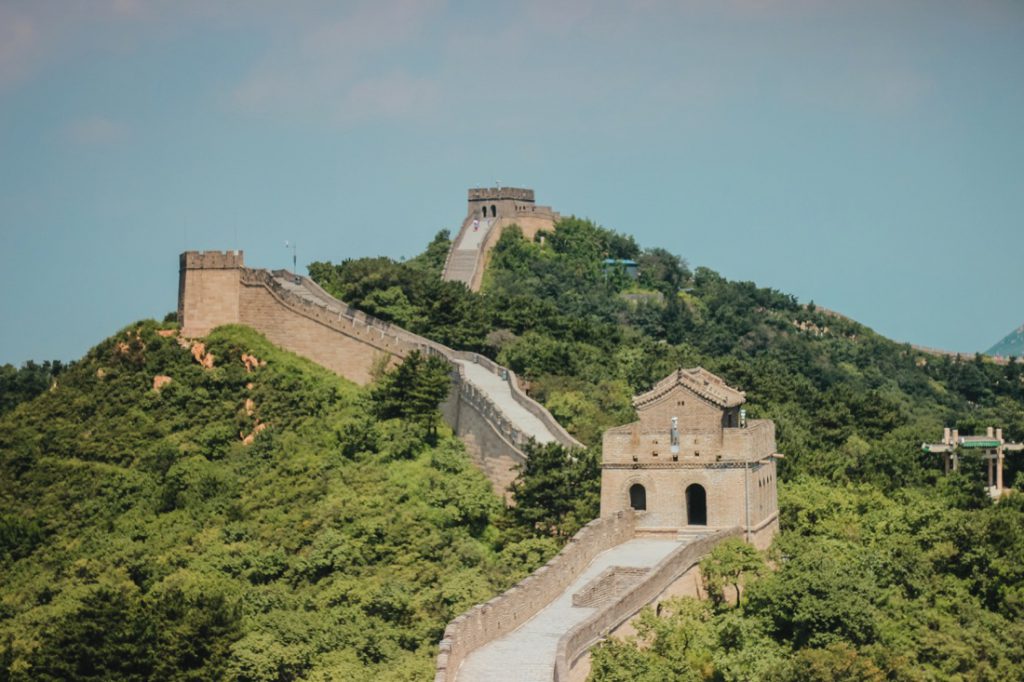The Great Wall winds along green hills under a pale blue sky