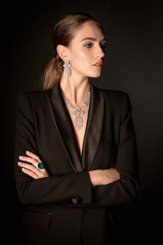 Người mẫu mặc vest đen trang sức kim cương và ngọc lục bảo