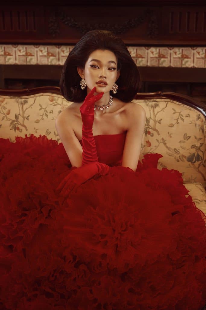 Người mẫu diện váy đỏ quyến rũ cùng găng tay dài trên ghế sofa cổ điển