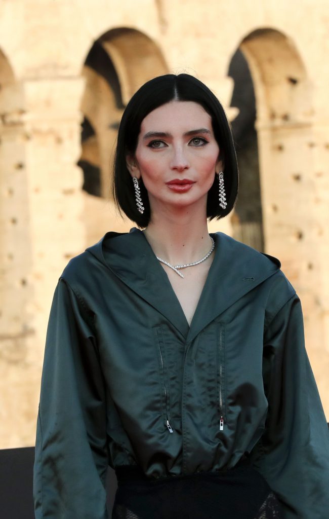 Người phụ nữ với trang phục xanh và trang sức BVLGARI nổi bật trước kiến trúc cổ