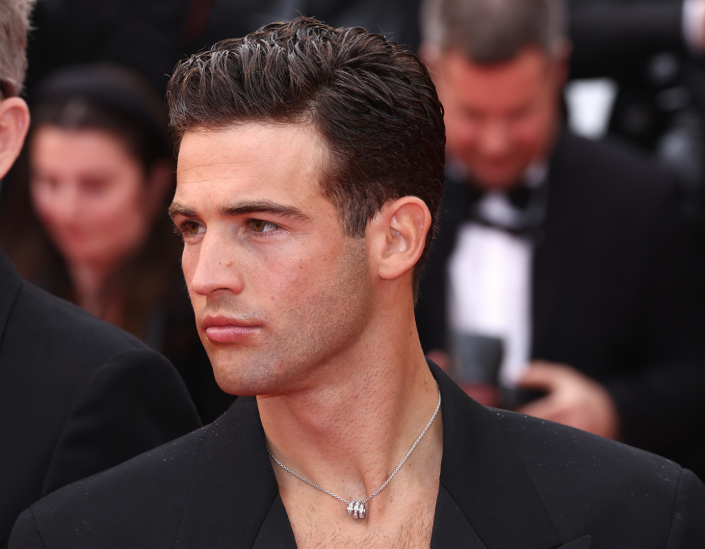 Một người đàn ông lịch lãm với vest đen và dây chuyền bạc tại LHP Cannes