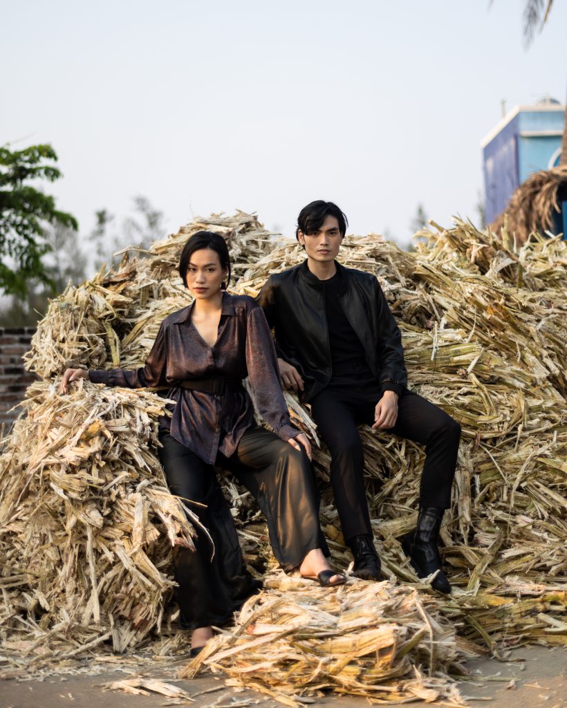 Nam nữ người mẫu ngồi trên đống mía lau trong trang phục hiện đại