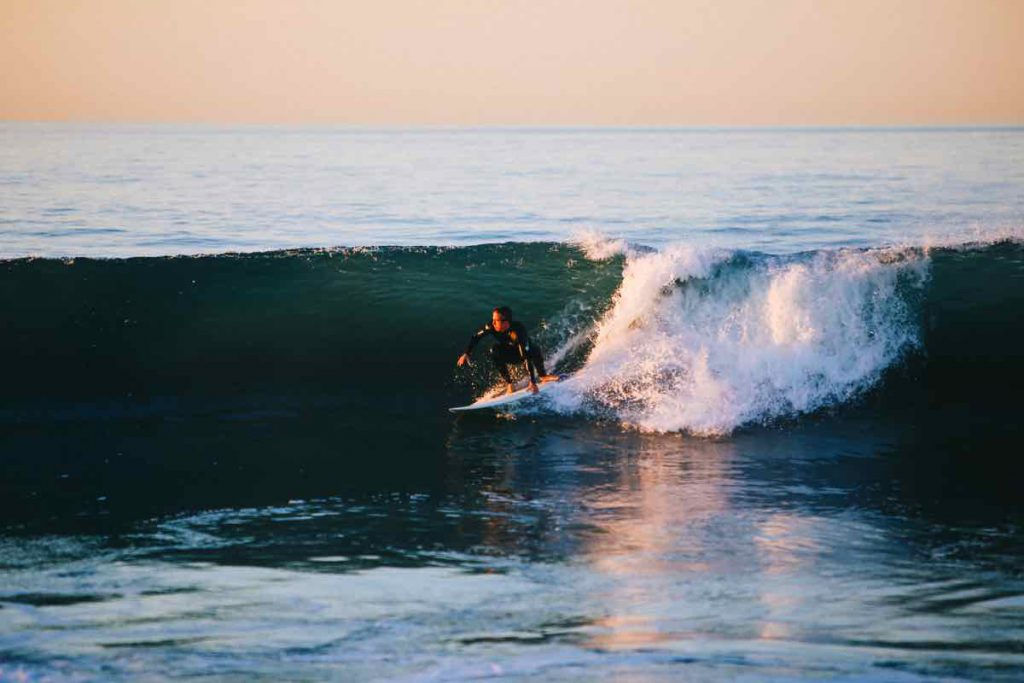 Vận động viên lướt sóng đang chinh phục một con sóng lớn dưới ánh nắng bình minh
