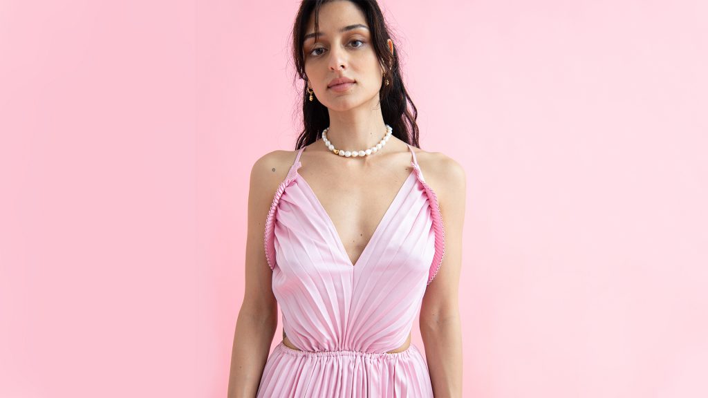 Người mẫu mặc váy hồng nhạt kiểu dáng gợi cảm trên nền hồng