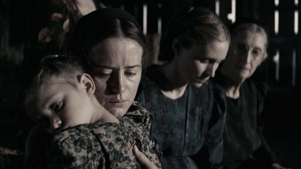 Người phụ nữ ôm trẻ nhỏ nhìn xa xăm trong khung cảnh u ám