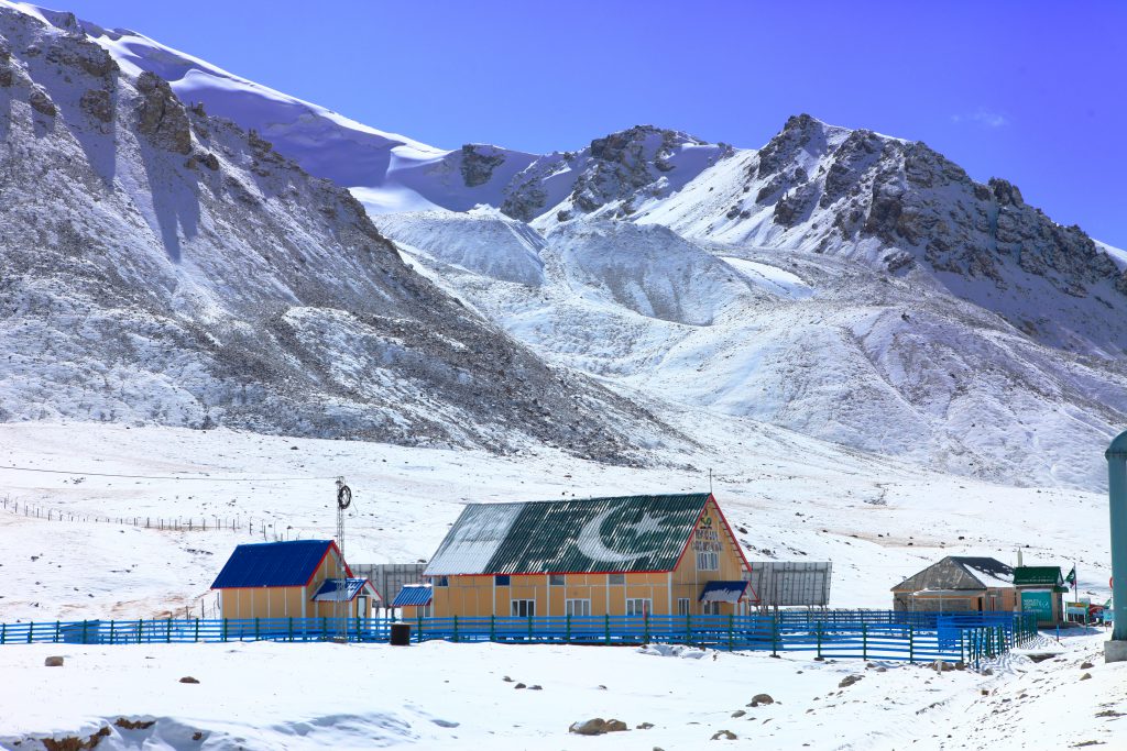 Snowy mountains rise behind colorful buildings in a winter landscape