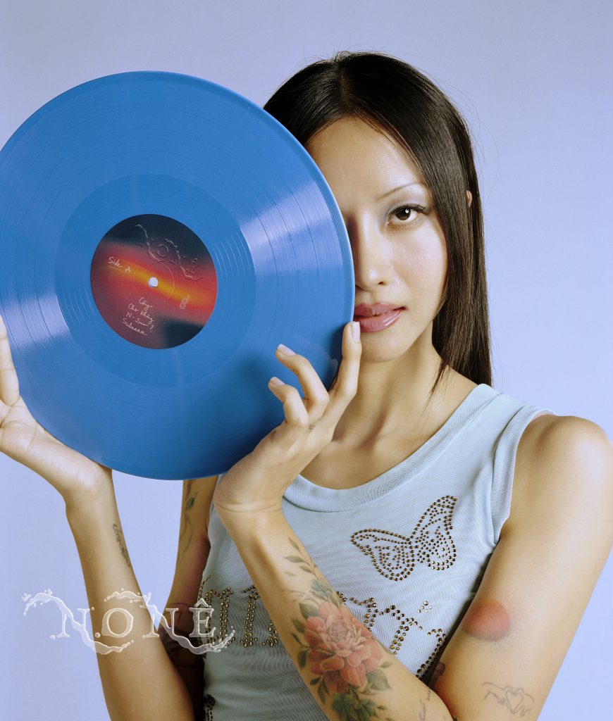 Cô gái trẻ cầm đĩa than màu xanh lam nhìn thẳng vào ống kính