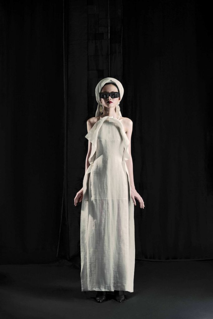 Người mẫu mặc váy trắng dài và đội khăn kín đáo đeo kính râm