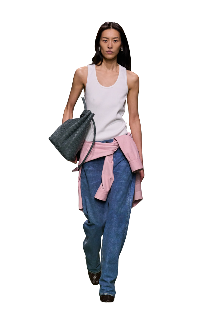 Người mẫu trình diễn trang phục gồm áo ba lỗ quần jeans và áo khoác buộc ngang hông cùng túi xách