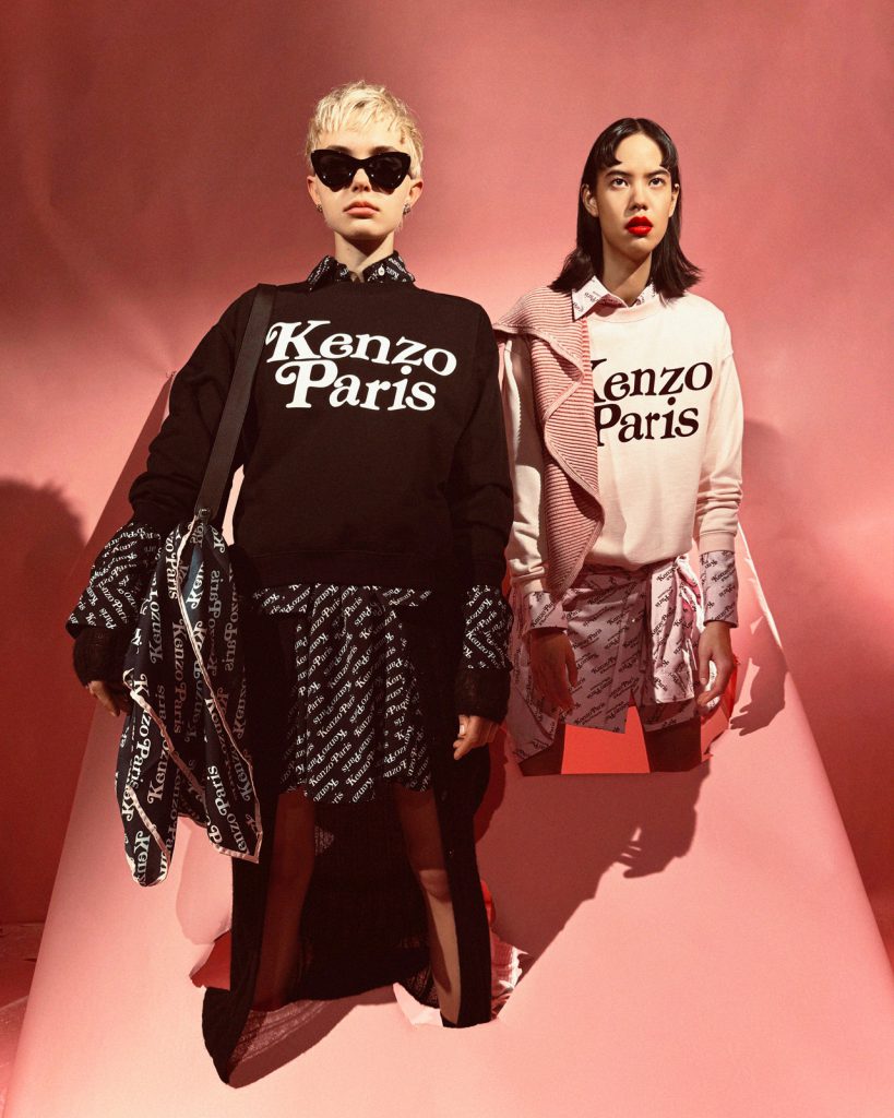 Hai người mẫu mặc trang phục Kenzo Paris họa tiết logo trên nền hồng phấn