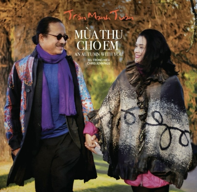 Trần Mạnh Tuấn và một người phụ nữ nắm tay đi dạo trong khung cảnh mùa thu lãng mạn