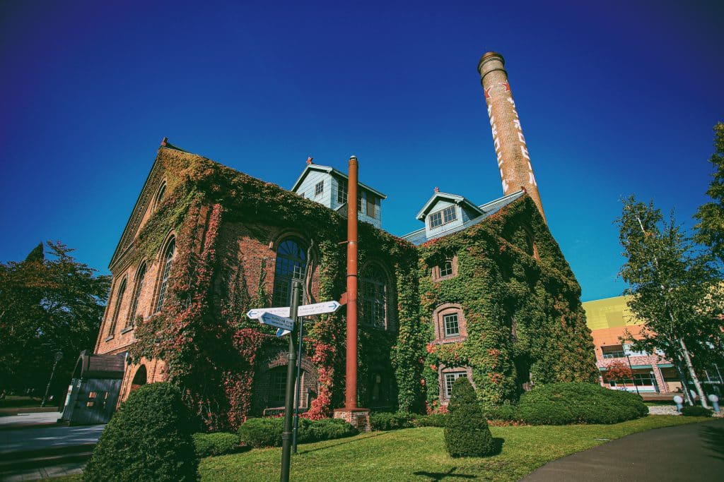 A brick building covered in ivy stands beneath a clear blue sky