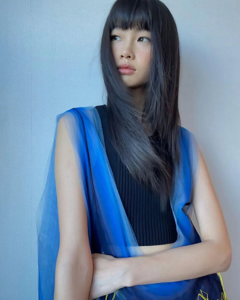 Cô gái trẻ với mái tóc đen dài và trang điểm nhẹ nhàng đang tạo dáng