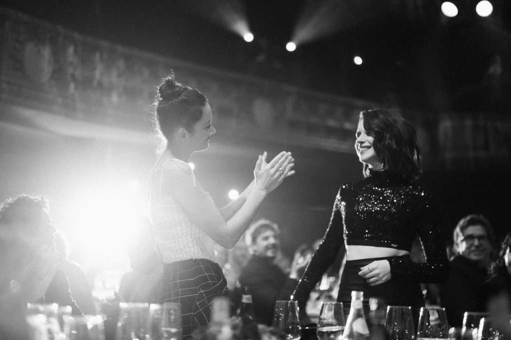 Hai phụ nữ vỗ tay chào nhau tại một sự kiện nghệ thuật sang trọng