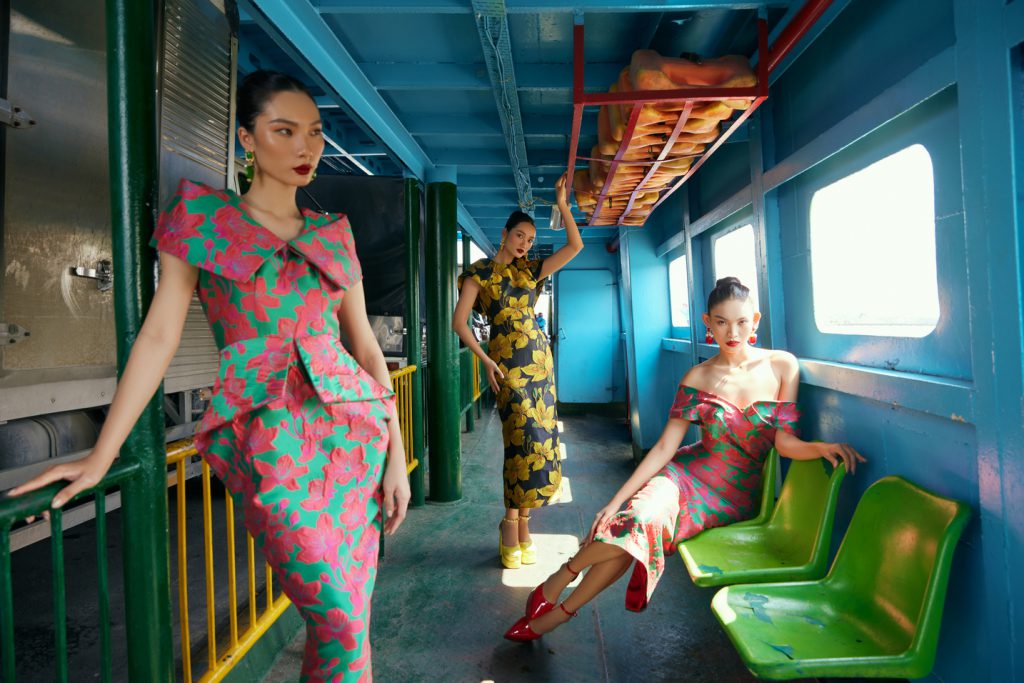 Ba người mẫu diện trang phục rực rỡ trong một khoang tàu xanh lam