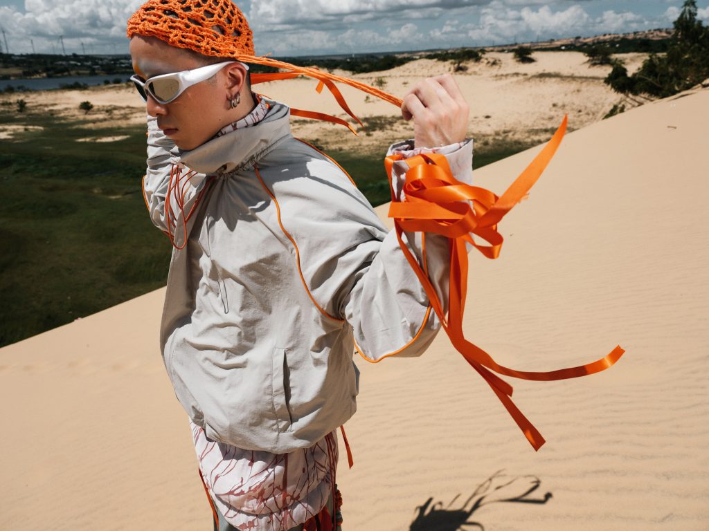 Người mẫu tạo dáng trên đồi cát với trang phục và phụ kiện độc đáo