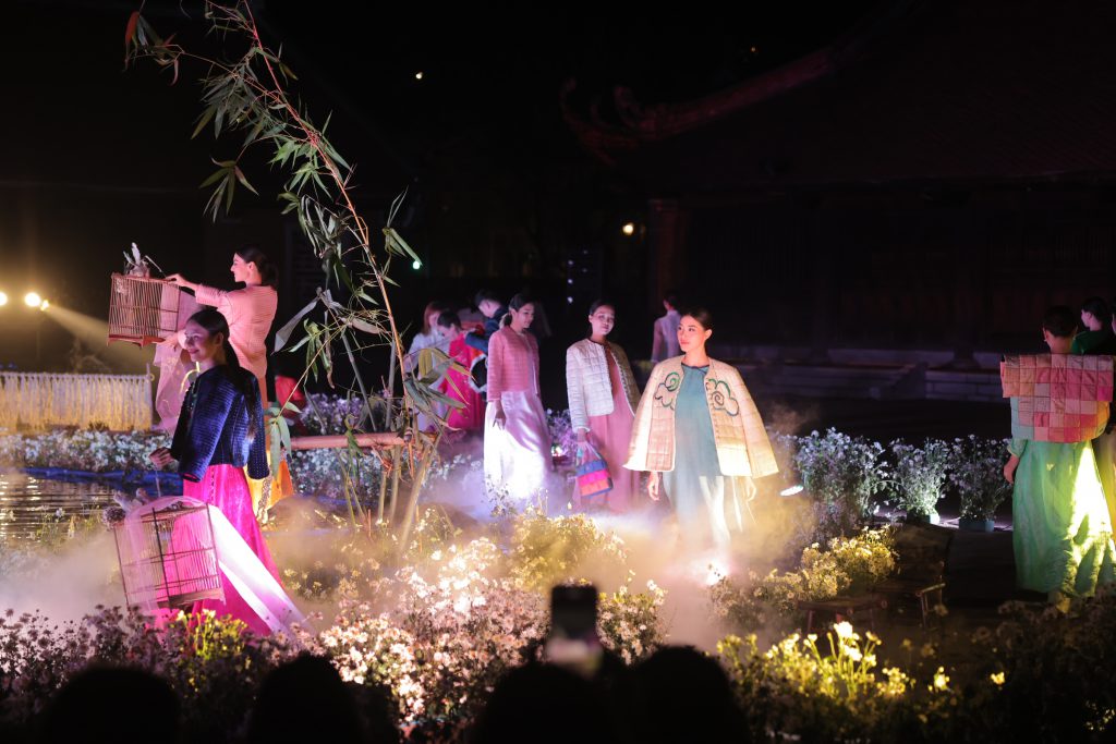 Các người mẫu trình diễn áo dài truyền thống trên sân khấu có khói và hoa trắng