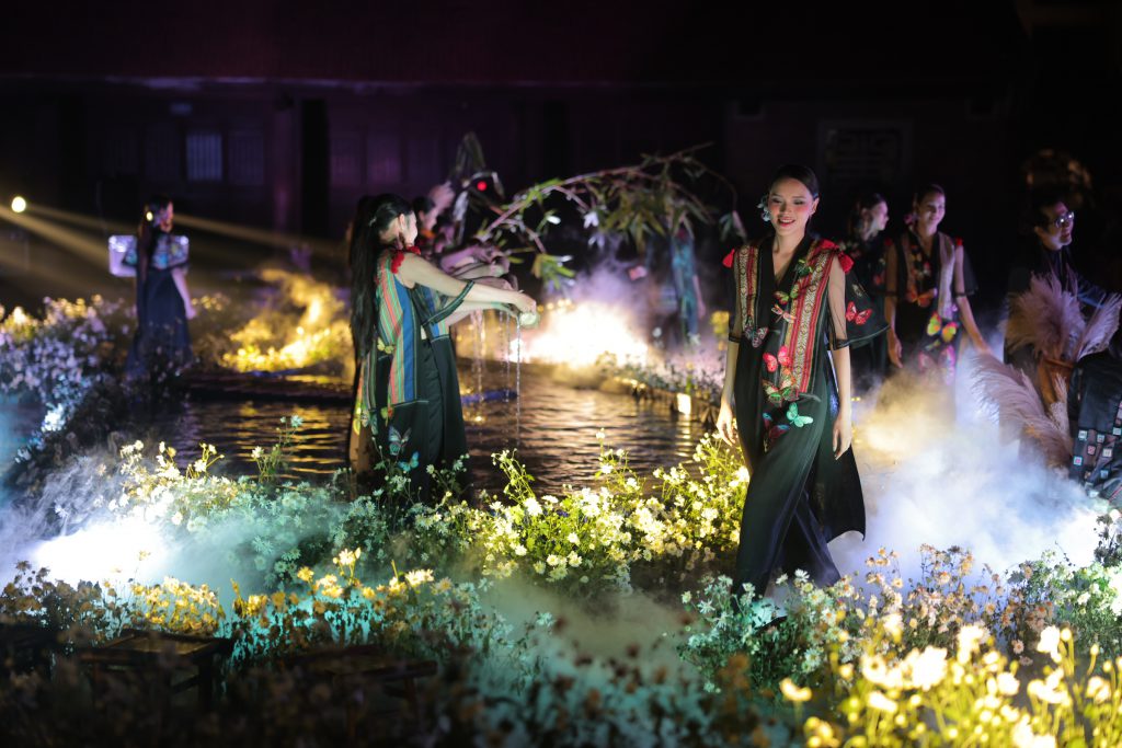 Người mẫu trình diễn trang phục dân tộc trên sàn diễn đầy hoa và ánh sáng huyền ảo