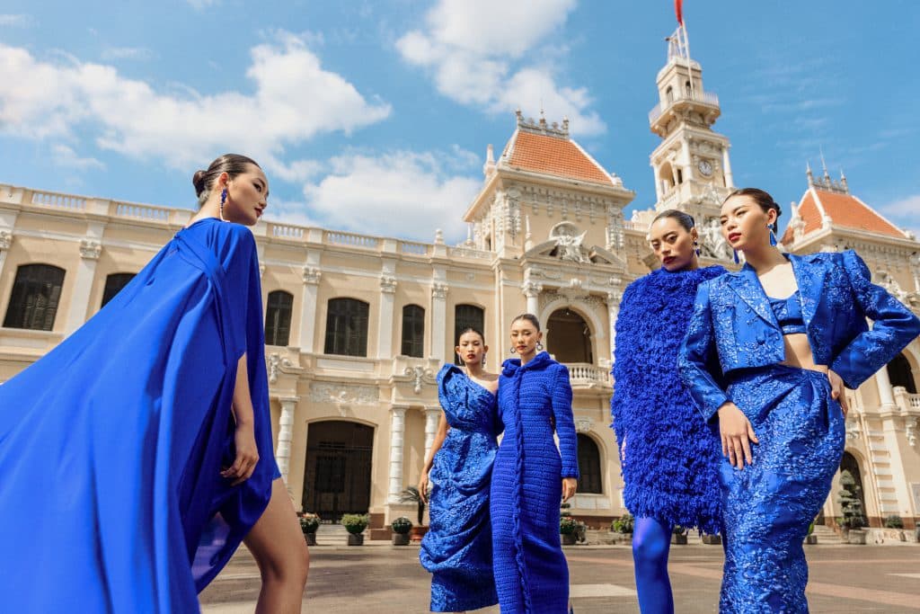 Nhóm người mẫu trình diễn trang phục màu xanh lam nổi bật trước tòa nhà lịch sử