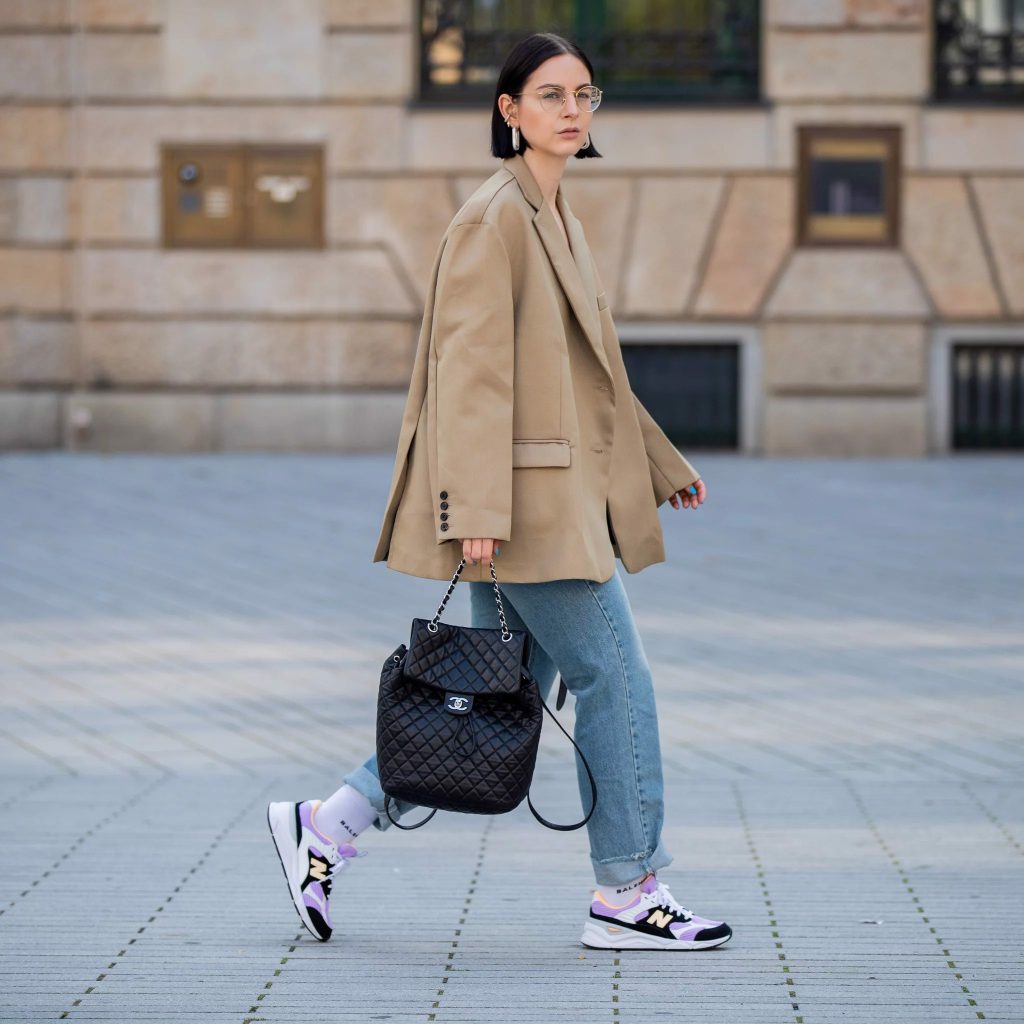 Cô gái mặc áo blazer và quần jean dáng rộng đi giày thể thao trên phố