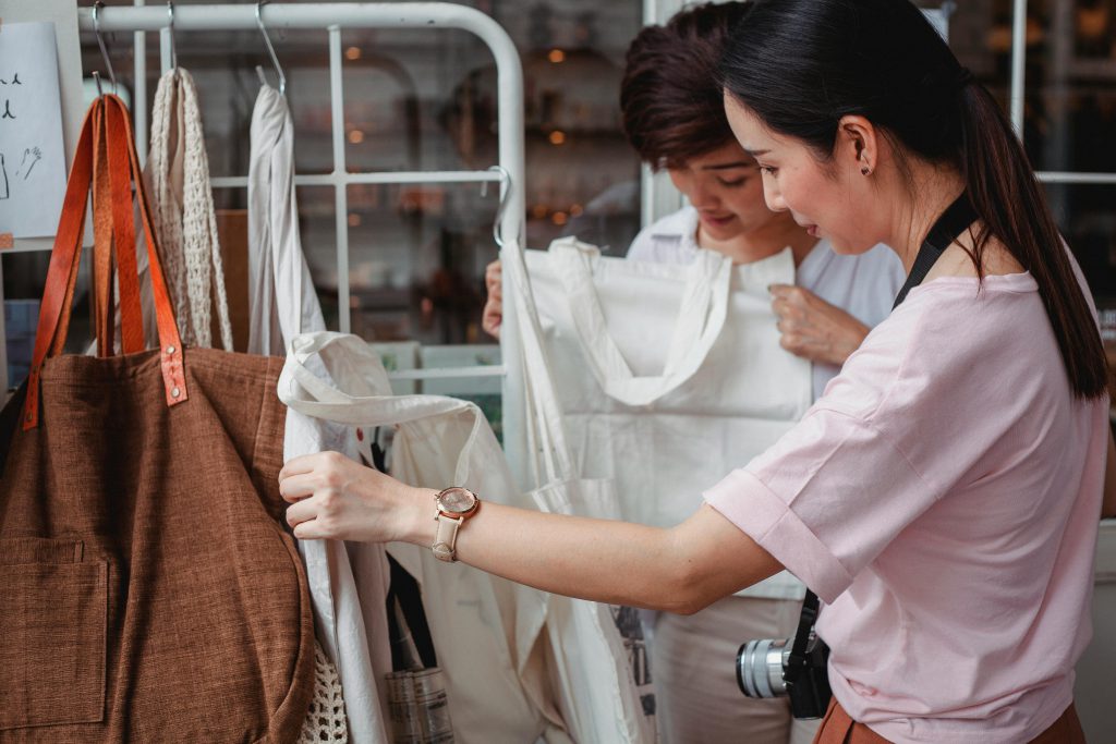 Hai phụ nữ trẻ đang chọn mua túi vải tại một cửa hàng thời trang thân thiện môi trường