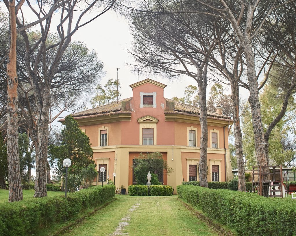 Một tòa nhà màu cam đào nổi bật giữa hàng cây thông xanh mướt và thảm cỏ xanh