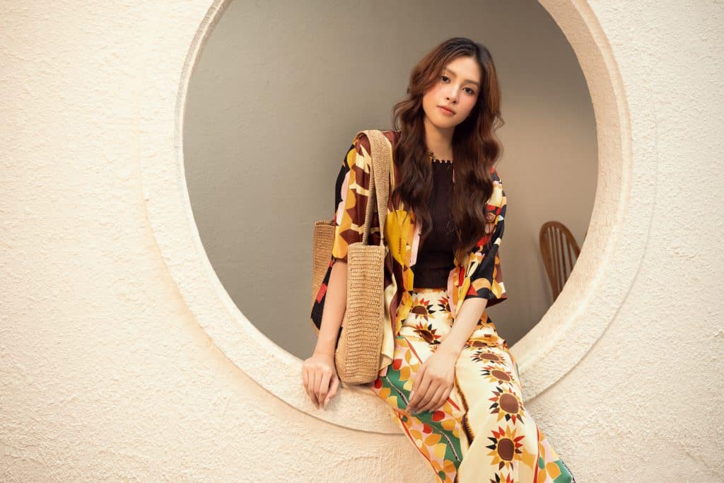 Tiểu Vy tươi tắn với trang phục Sandro họa tiết hoa hướng dương cùng túi cói