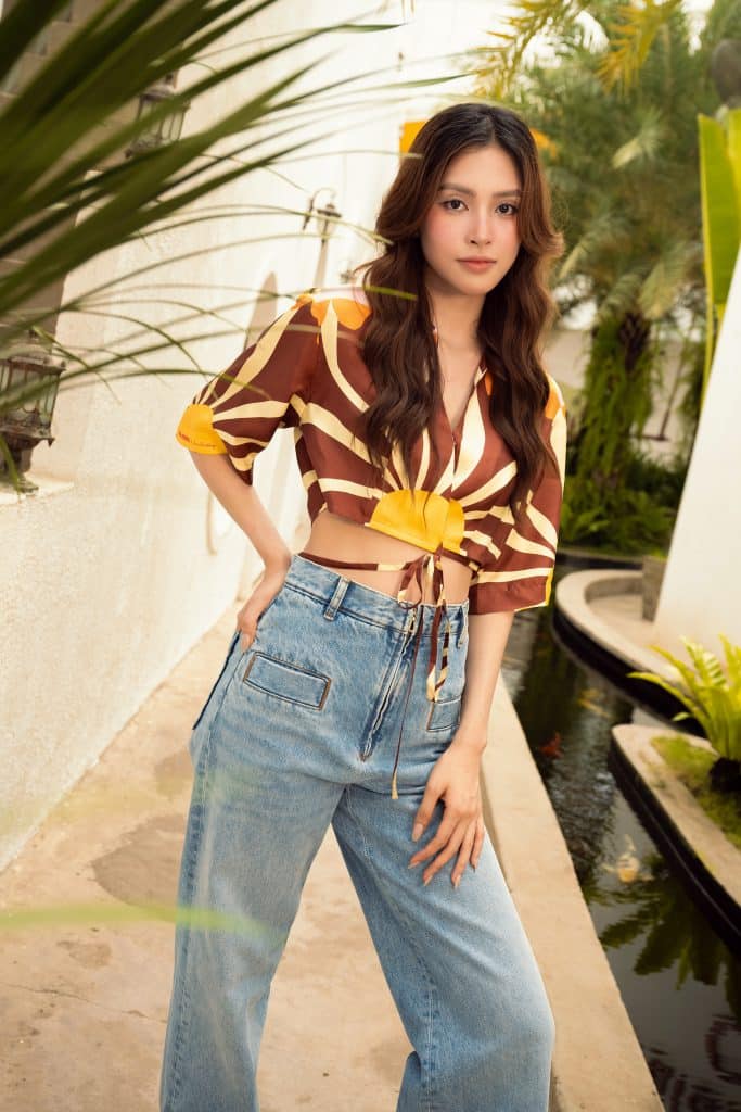 Tiểu Vy diện áo crop top họa tiết mặt trời và quần jean ống rộng dạo chơi trong khu vườn xanh mát