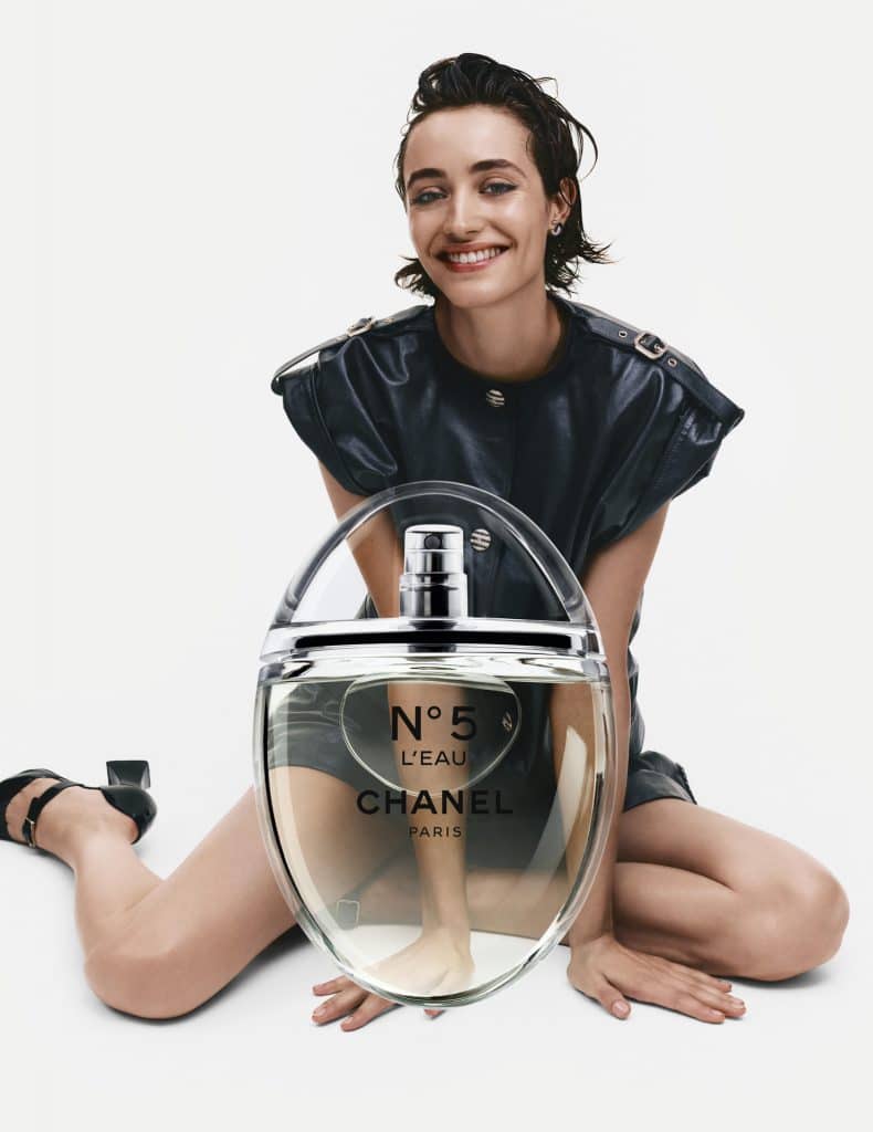 Người mẫu tươi tắn ngồi cạnh chai nước hoa Chanel N°5 L'Eau lớn