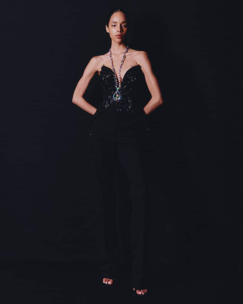 Người mẫu mặc trang phục đen quyến rũ với dây chuyền nổi bật trên nền tối
