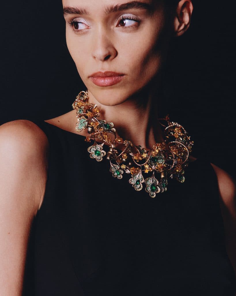 Người mẫu đeo vòng cổ kim cương và ngọc lục bảo lấp lánh trên nền đen