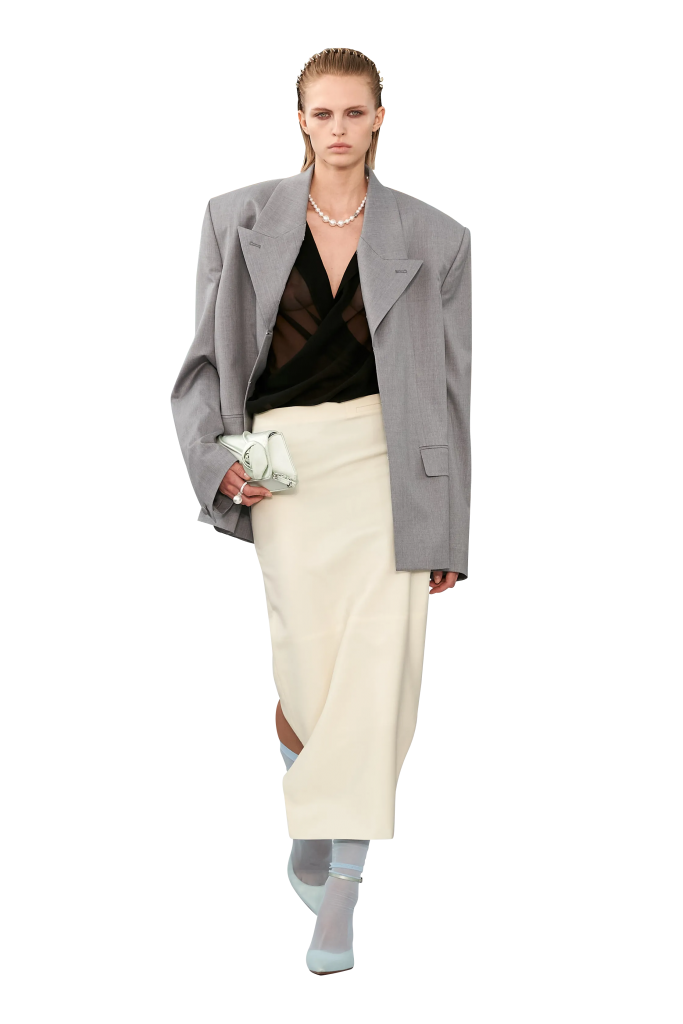 Người mẫu trình diễn trang phục áo blazer khoác ngoài áo đen và chân váy kem