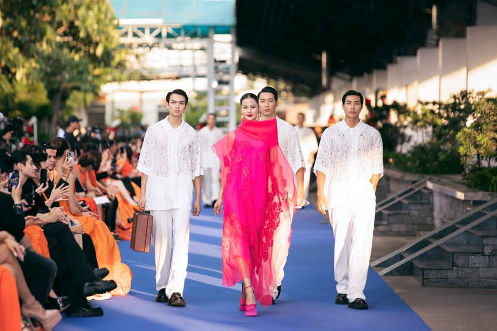 Người mẫu trình diễn thời trang trên sàn diễn màu xanh tại sân ga