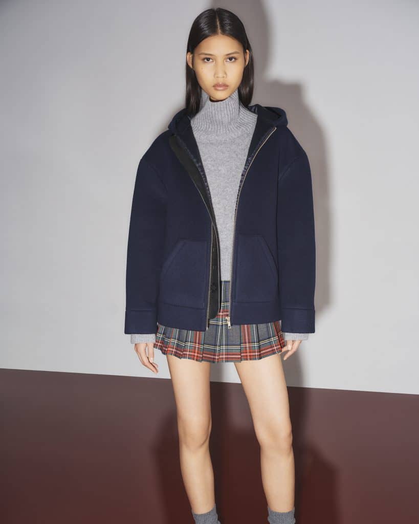 Người mẫu mặc áo khoác xanh navy và váy xếp ly họa tiết caro