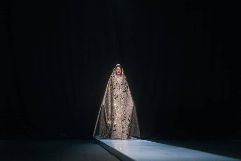Người mẫu trình diễn trang phục lộng lẫy trên sàn diễn tối màu