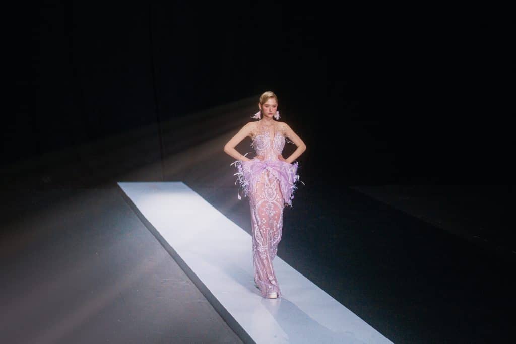 Người mẫu trình diễn váy tím lộng lẫy trên sàn catwalk sáng đèn