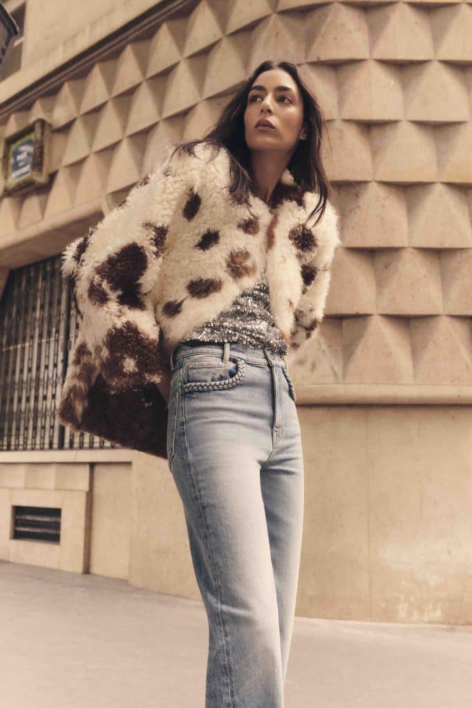 Người mẫu mặc áo khoác lông báo và quần jeans sáng màu trên phố