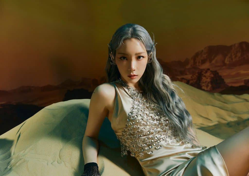 Cô gái với mái tóc màu tro xám đang tạo dáng trên đồi cát vàng