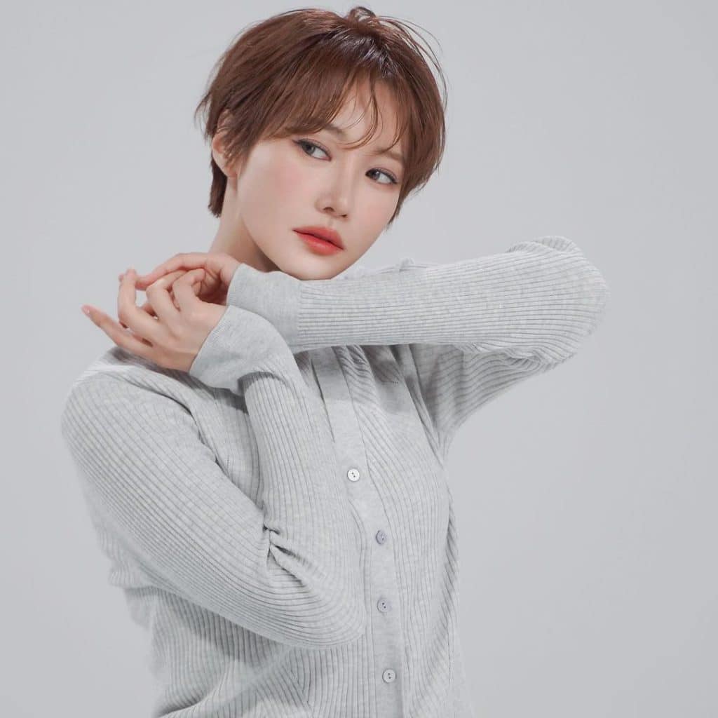 Cô gái trẻ với tóc ngắn và áo len xám nhìn thẳng vào ống kính