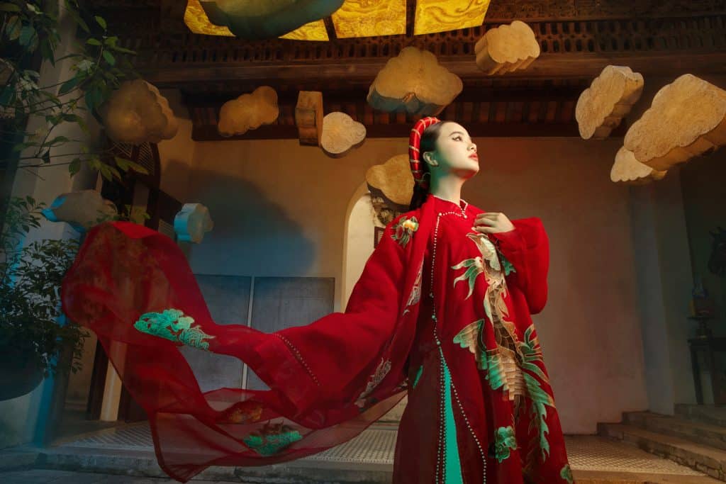 Người mẫu mặc áo dài đỏ thêu phượng vàng duyên dáng dưới mái vòm cổ kính