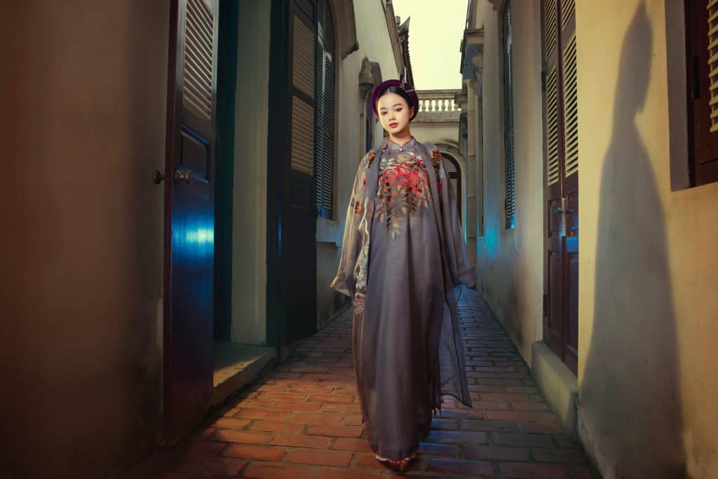 Người mẫu mặc áo dài thêu phượng hoàng sải bước giữa con hẻm nhỏ cổ kính