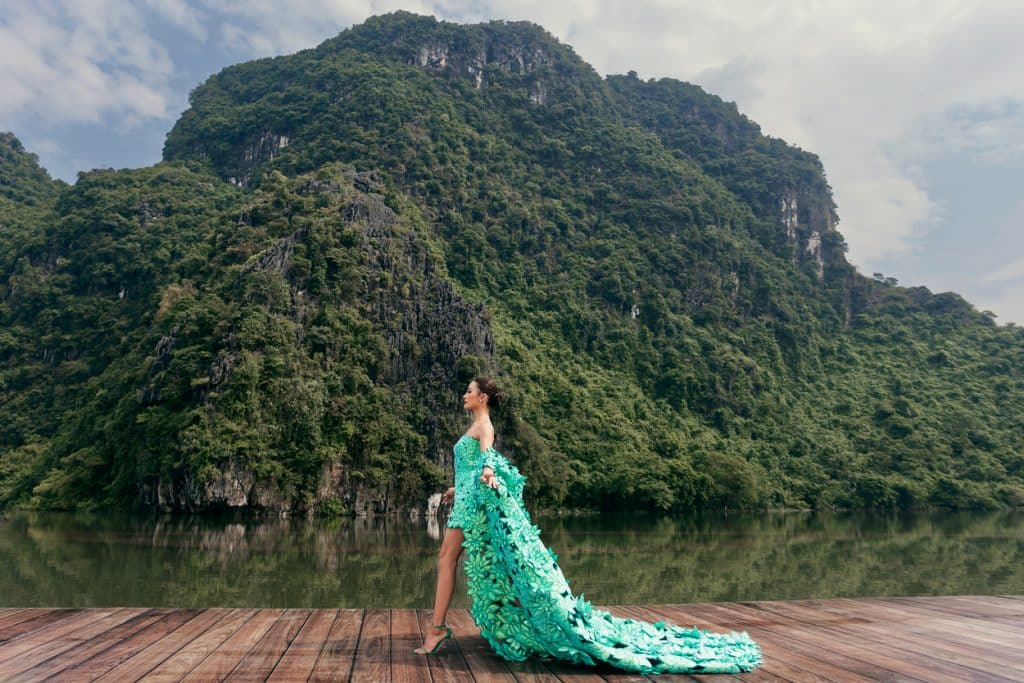 Người mẫu diện váy xanh lộng lẫy trên cầu gỗ giữa khung cảnh núi non Tràng An hùng vĩ