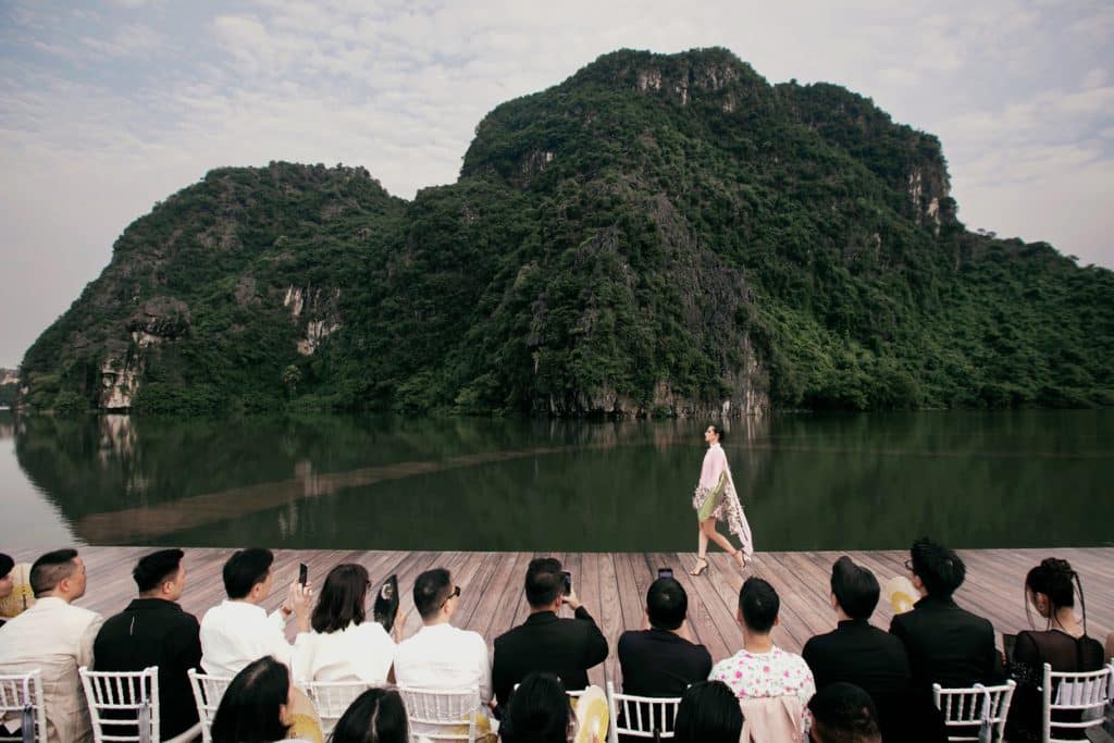 Người mẫu trình diễn trên sàn catwalk gỗ trước cảnh quan núi non Tràng An hùng vĩ