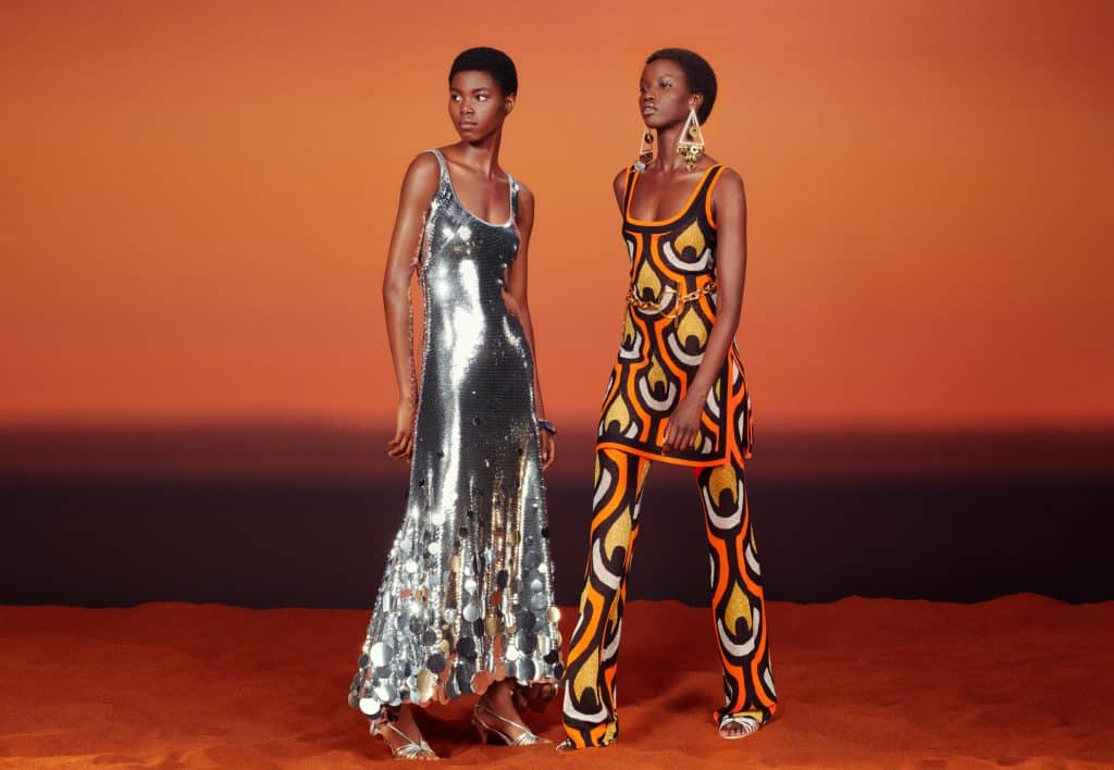 Hai người mẫu da màu diện trang phục lấp lánh và họa tiết nổi bật trên nền cam
