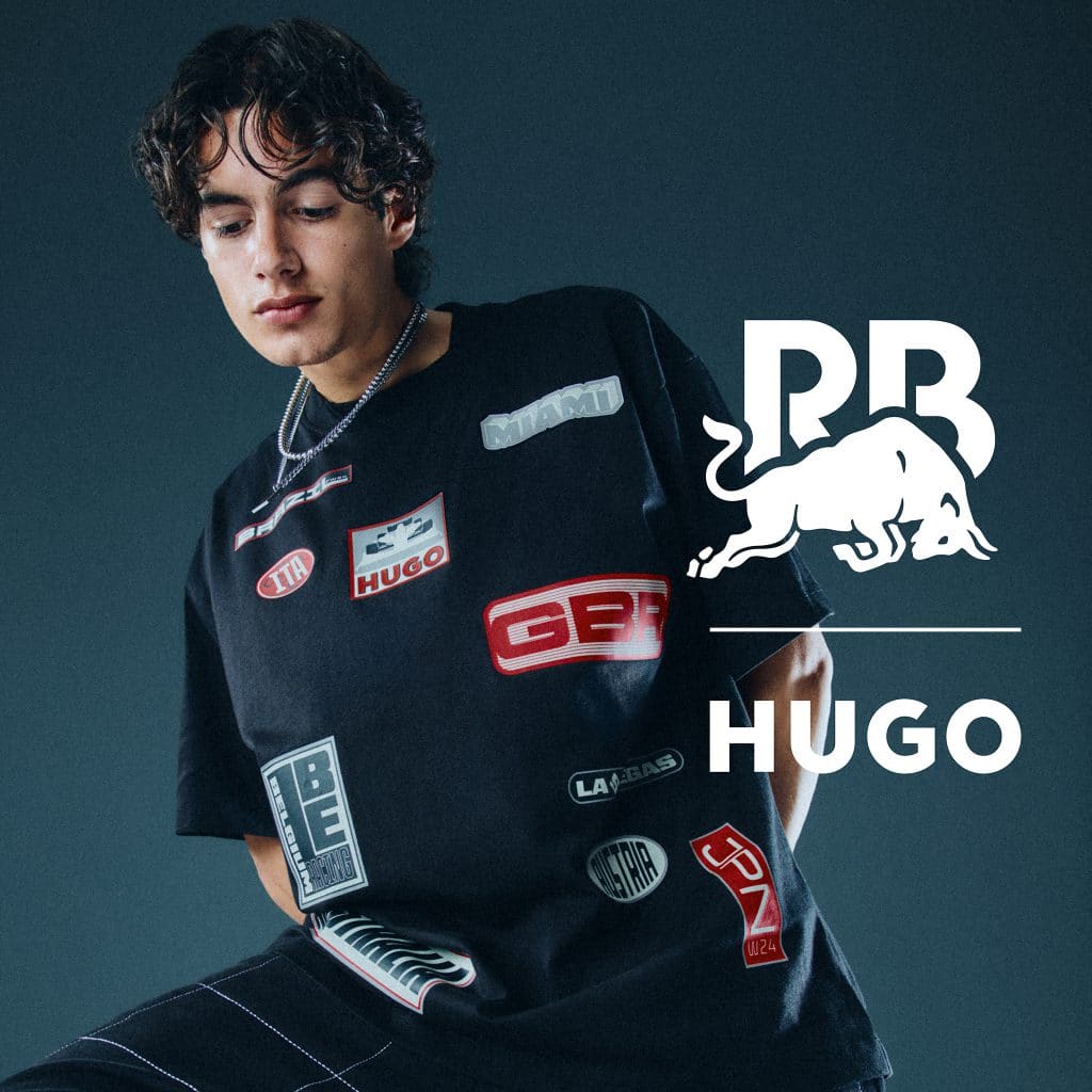 Người mẫu mặc áo khoác đen nhiều miếng vá mang phong cách đua xe công thức 1