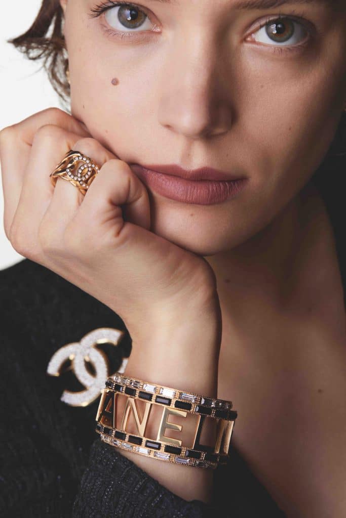 Người mẫu với trang sức vàng và nhẫn đính đá trên tay áo đen