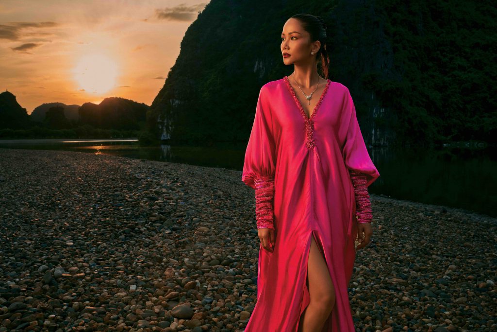 Người mẫu mặc váy lụa hồng nổi bật trên nền hoàng hôn và bãi đá