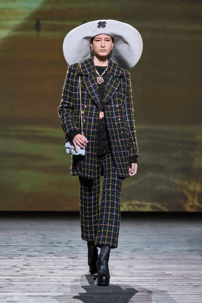 Người mẫu trình diễn trang phục kẻ caro và mũ rộng vành trên sàn diễn thời trang