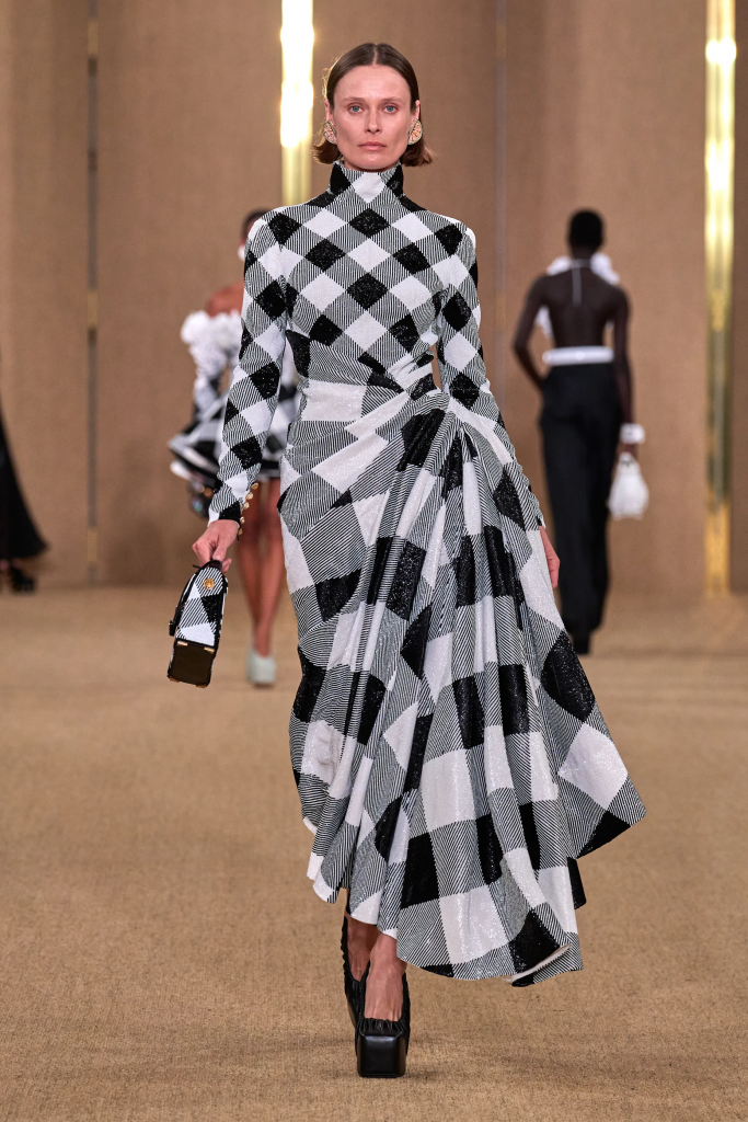 A model walks the runway wearing a long black and white checkered dress